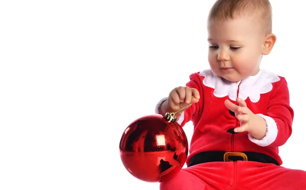 Malé dítě chlapec batole v Santa Claus vánoční kostým a klobouk šťastný úsměv s červeným dárkem míč jedle dekorace připravena k oslavě — Stock fotografie