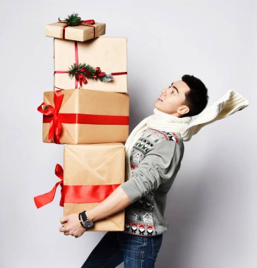 Genç yakışıklı adam bir sürü kırmızı yılbaşı hediyesiyle Noel yemeği için acele ediyor. Neşeyle zıplar zıplar
