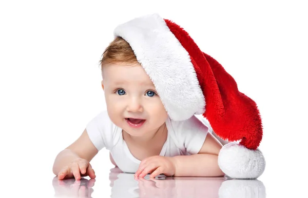 새해 컨셉이야. 붉은 크리스마스 산타 모자를 쓴 채누워 있는 아기가 혼자 서 미소짓는 모습 — 스톡 사진