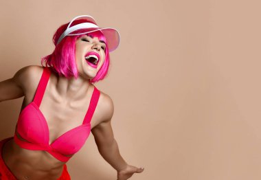 Pembe saçlı, şapkalı, çılgın, güzel bir kız. Sevinçle bağırıyor.