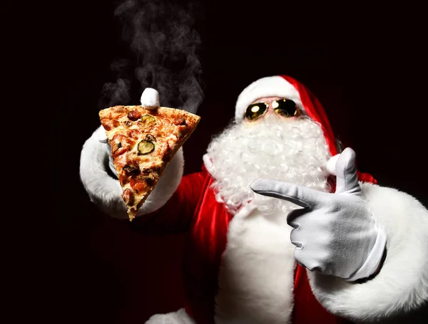 Szczęśliwy i hojny Święty Mikołaj trzyma na parze kawałek gorącej pizzy. Nowy rok i Wesołych Świąt — Zdjęcie stockowe