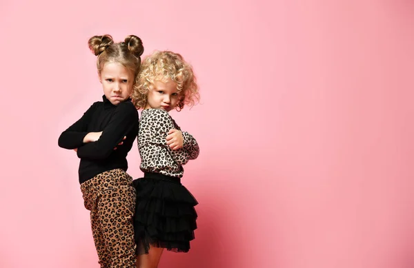 Two kid girls best friends sisters in leopard print clothes are standing with their backs to each other, looking angrily — Stock Photo, Image
