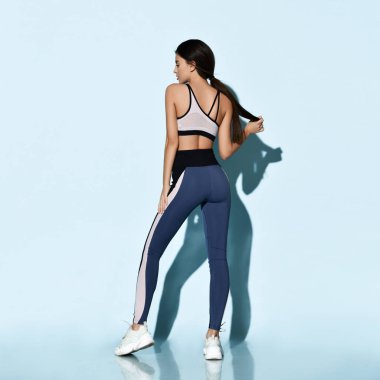 Spor kıyafetli güzel bir bayan açık mavi üzerinde spor egzersizleri yapıyor. 