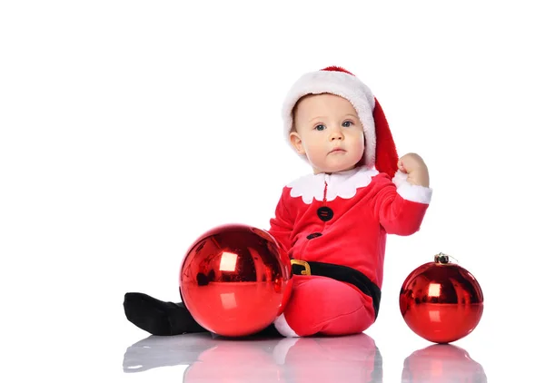 Noel Baba kostümü içinde küçük çocuk Noel Baba ve şapkalı mutlu bir gülümseme ile kırmızı hediye balosu köknar süslemesini kutlamaya hazır. — Stok fotoğraf