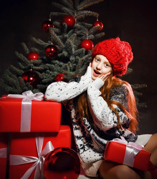 2020 년 새해를 맞아 크리스마스 트리를 붉은 겨울 모자를 쓰고 선물 상자를 장식하는 소녀 — 스톡 사진