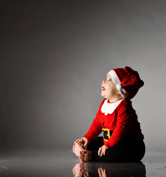 산타 클로스 복장을 하고 복제품 공간의 코너를 올려다보며 맨 발로 웃는 행복 한 소년 이 산타 클로스에 앉아 있다. — 스톡 사진