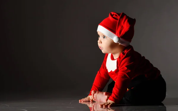 Fascynujące boso niemowlę chłopiec maluch siedzi w stroju Świętego Mikołaja na lodzie w ciemności patrząc na przestrzeń kopiowania — Zdjęcie stockowe