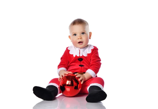 Dítě chlapec batole v Santa Claus kostým je držení vánoční stromeček červená koule jedle dekorace s oběma rukama vzhlíží — Stock fotografie