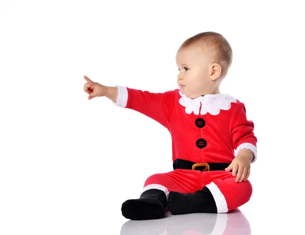 Kojenec chlapec batole v červeném Santa Claus vánoční kostým ukazuje prstem na něco dotýká celé tělo na bílém — Stock fotografie