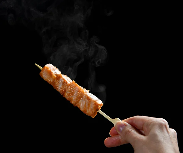 Grilovaný losos gril bbq na dřevěné tyčce s kouřem páry v ruce — Stock fotografie