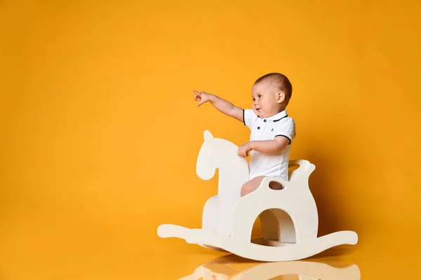 Oyuncu erkek bebek çocuk, çocuklar için tahta atına biniyor ve bedava fotokopi alanını işaret ediyor. — Stok fotoğraf