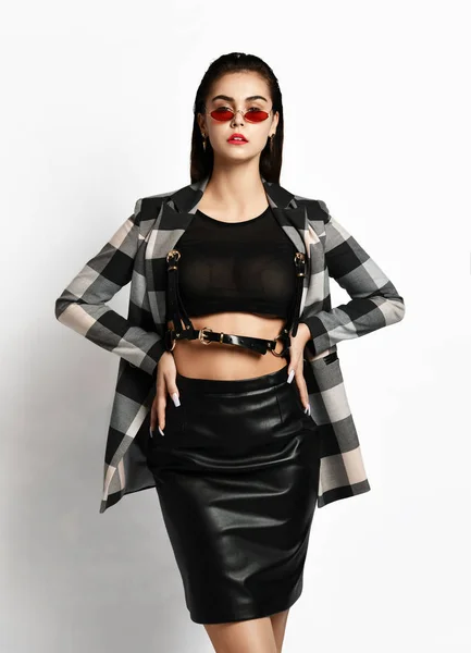 Young glamorous modern girl in a checkered jacket and black skirt wear red fashion glasses posing — 스톡 사진