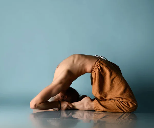 Vieil homme mature pratiquant le yoga classique asana étirement pose dans la salle de fitness sur bleu clair — Photo