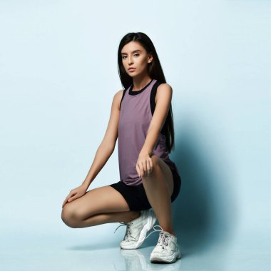 Spor kıyafetleriyle spor yapan güzel bir kadın açık mavi üzerinde spor egzersizleri yapıyor. 