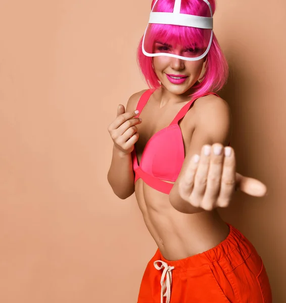 Jovem mulher atlética positiva com cabelo rosa em sportswear brilhante de pé e pedindo para vir sobre fundo da parede amarela — Fotografia de Stock