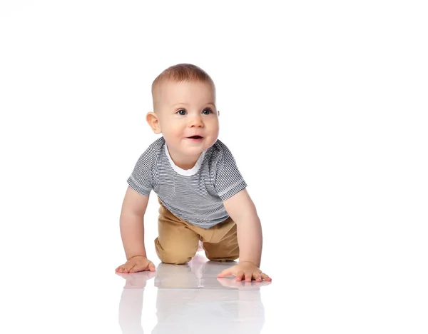 Interested infant child boy in t-shirt and green pants is crawling on all fours, looking at free copy space on white — Stock Photo, Image