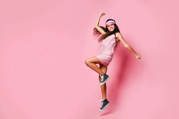 若いです女の子でAキャップとピンクの縞模様のドレスありますジャンプ楽しいですショーA勝者運サイン保持手上のピンク — ストック写真