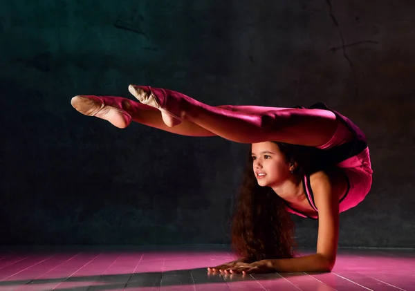 Молодая девушка гимнастка делает упражнения гимнастика стоять на локтях с отклонением в нижней части спины согнуты в пояснице — стоковое фото