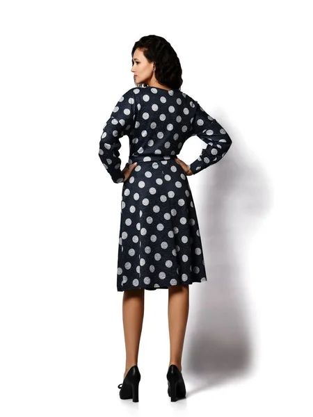Young beautiful brunette curly smiling woman model in stylish vintage dark dotted midi dress and shoes standing backwards — 스톡 사진