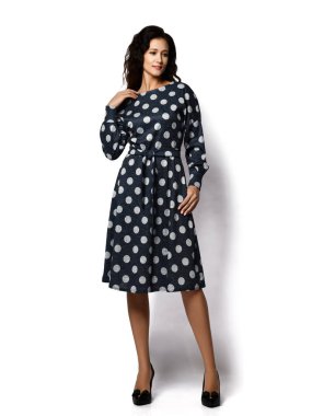 Genç, güzel, kıvırcık, kıvırcık saçlı, şık, esmer bir kadın model. Şık, siyah, benekli bir elbise ve ayakkabıyla.