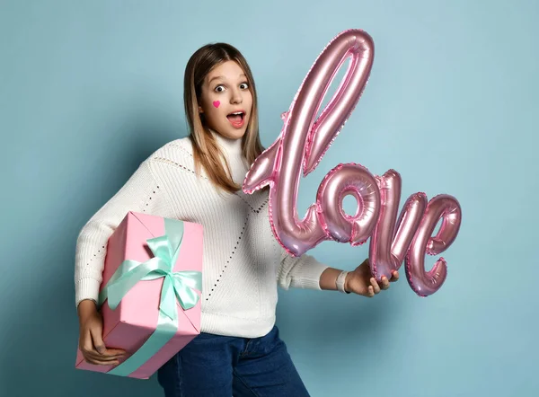 Здивована дівчина-підліток тримає любовну рожеву кульку і подарункову коробку під рукою в день валентинки. Повітряна куля кохання — стокове фото