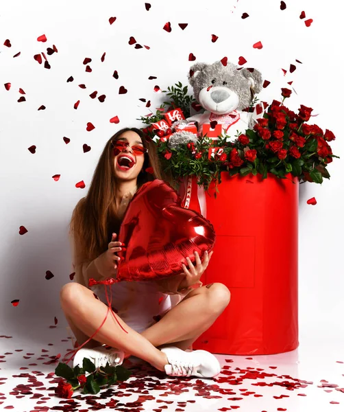 Young beautiful brunette woman celebrate valentines day or birthday party sitting holding red heart balloon with hears — 스톡 사진