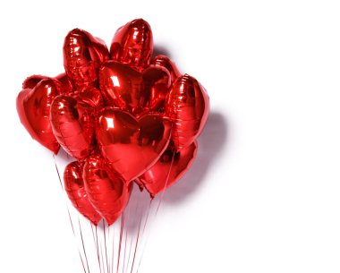 Beyaz arka planda kırmızı renkli metal kalp şeklinde folyo balonları var. Hava balonu seti Sevgililer Günü
