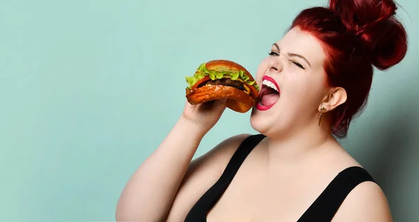 Happy size-plus mulher gorda com sobrepeso feliz segurar hambúrguer cheeseburger churrasco sanduíche com carne em pastel turquesa — Fotografia de Stock
