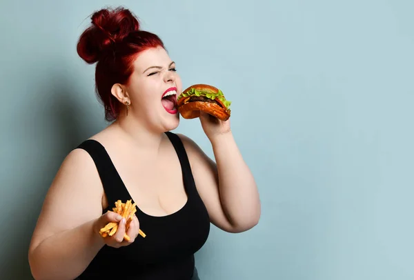 Счастливая толстая женщина счастливый держать бургер чизбургер сэндвич с говядиной и картофель фри в руке — стоковое фото