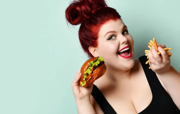 Happy overweight fat woman happy hold burger cheeseburger sandwich met rundvlees en frietjes in de hand — Stockfoto