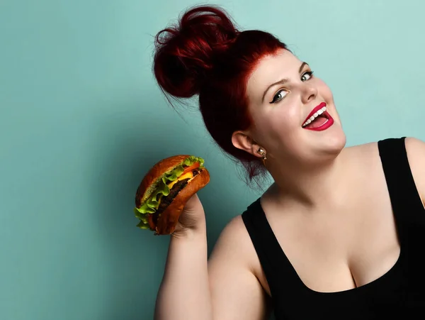 Щасливий розмір плюс надмірна вага товста жінка щаслива тримайте бургер з чізбургер барбекю сендвіч з яловичиною на пастельному бірюзовому — стокове фото