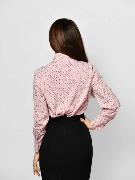 Zadní pohled mladé brunetky ženy ve formální růžové blůzy košile a černé těsné sukně přes šedé pozadí — Stock fotografie