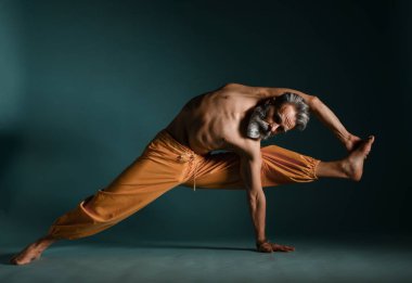 Gri sakallı yaşlı adam yoga, pilates, spor, esneme egzersizi, asana ya da yerde denge egzersizi yapıyor.
