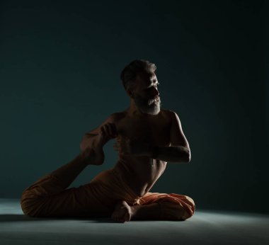 Gri sakallı yaşlı adam yoga, pilates, spor, esneme egzersizi, asana ya da yerde denge egzersizi yapıyor.