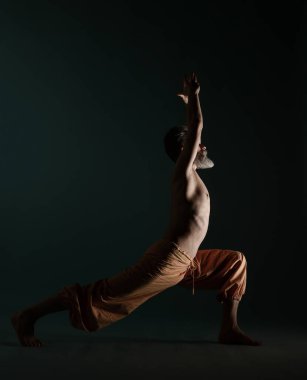 Gri sakallı yaşlı adam yoga, pilates, spor, esneme egzersizi, asana ya da yerde denge egzersizi yapıyor.