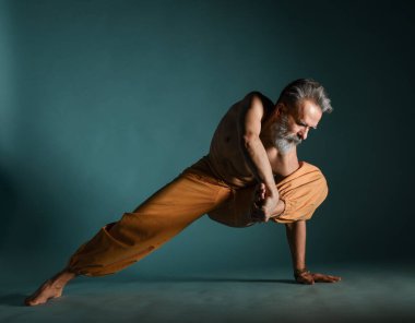 Gri sakallı yaşlı adam yoga, pilates, spor, esneme egzersizi, asana ya da yerde denge egzersizi yapıyor.
