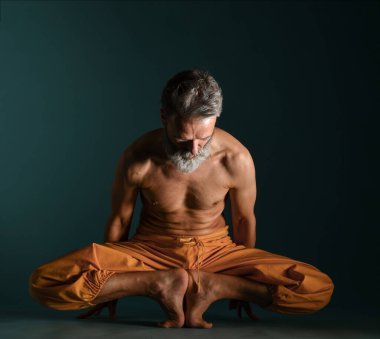 Gri sakallı yaşlı adam yoga, pilates, spor, esneme egzersizi, asana ya da yerde denge egzersizi yapıyor.