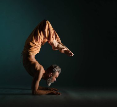 Gri sakallı yaşlı adam yoga, pilates, spor, esneme egzersizi, asana ya da yerde denge egzersizi yapıyor.