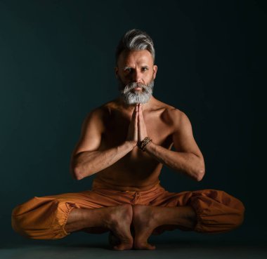 Gri sakallı yaşlı adam yoga, pilates, spor, esneme egzersizi, asana ya da yerde denge egzersizi yapıyor.
