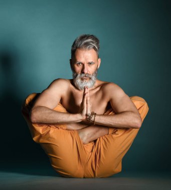 Gri sakallı yaşlı adam yoga, pilates, spor, esneme egzersizi, asana ya da yerde denge egzersizi yapıyor.