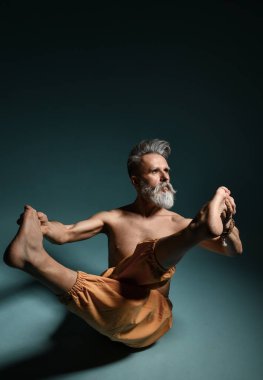 Gri sakallı yaşlı adam yoga, pilates, spor, esneme egzersizi, asana ya da yerde denge egzersizi yapıyor.