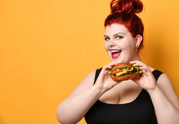 Happy overgewicht dikke vrouw gelukkig hold hamburger cheeseburger sandwich met rundvlees in de hand op geel — Stockfoto