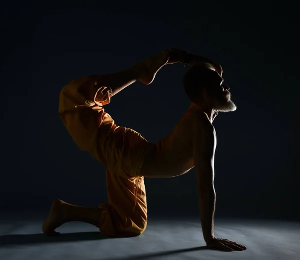 Le vieil homme à la barbe grise faisant du yoga, des pilates, de l'entraînement physique, des exercices d "étirement, de l'asana ou de l" équilibre au sol — Photo