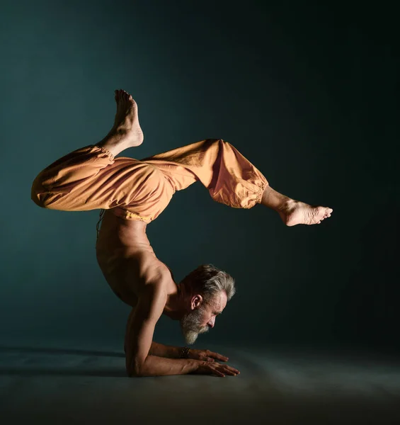 Le vieil homme à la barbe grise faisant du yoga, des pilates, de l'entraînement physique, des exercices d "étirement, de l'asana ou de l" équilibre au sol — Photo