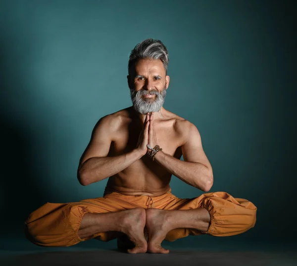 Gammal man med grått skägg gör yoga, pilates, fitness träning, stretching motion, asana eller balans träning på golvet — Stockfoto