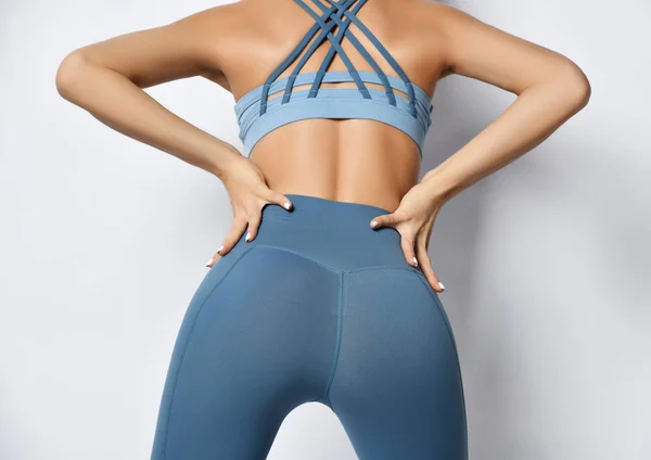 Sporty girl ass buttocks in pastel blue sportswear stands stand and touch herself on white — Stock Photo, Image
