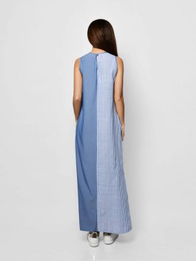 Genç esmer kadın yeni moda uzun Maxi yazlık gri çizgili elbisesiyle geri geri poz veriyor.