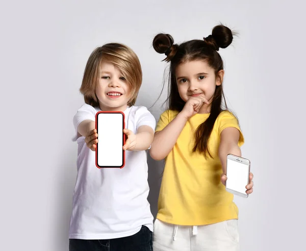 Two kids boy and girl brother and sister playing with mobile phone show blank screen of cellphone with free text copy — Stock Photo, Image
