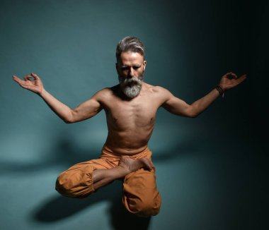 Gri sakallı yaşlı adam yoga yapıyor, pilates yapıyor, spor yapıyor, esneme egzersizleri yapıyor, asana havada duruyor ya da yerde denge çalışması yapıyor.