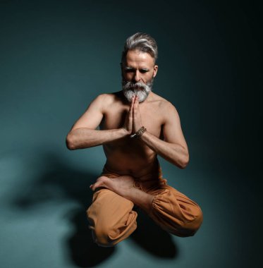 Gri sakallı yaşlı adam yoga yapıyor, pilates yapıyor, spor yapıyor, esneme egzersizleri yapıyor, asana havada duruyor ya da yerde denge çalışması yapıyor.